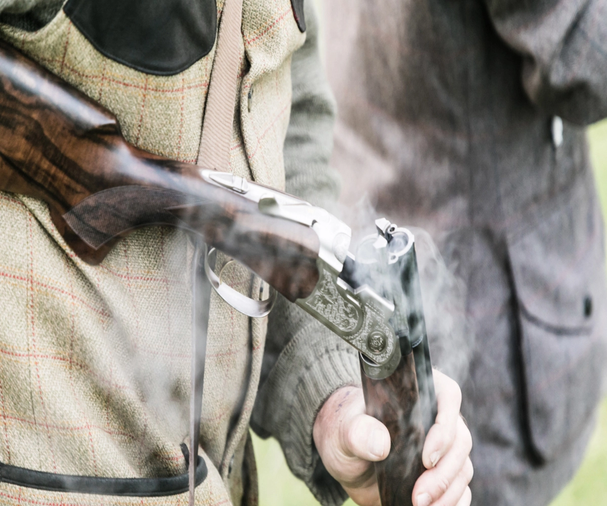 A hunting enthusiast breaks a smoking rifle